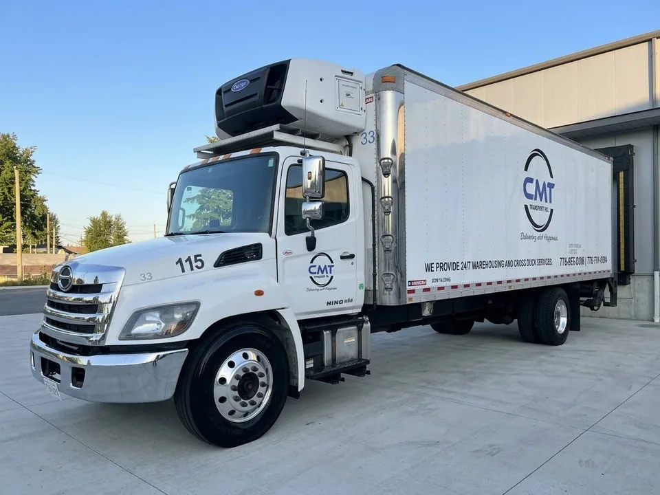 White C M T Transport refrigerated straight truck at a loading dock