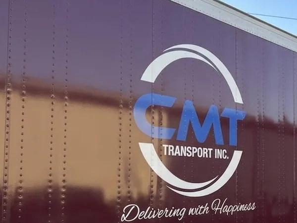 C M T Transport logo and Delivering With Happiness slogan on a branded trailer